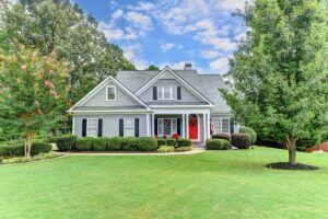 Gray craftsman-style home with a red front door and a manicured front lawn