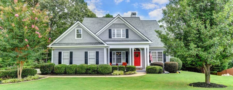 Gray craftsman-style home with a red front door and a manicured front lawn